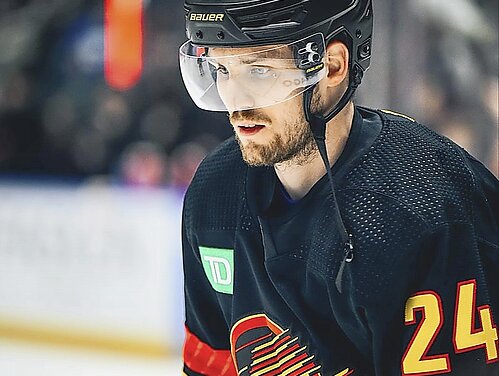 Pius Suter auf dem Hockeyfeld, mit schwarzem Helm und gelber Beschriftung sowie dem schwarz-rot-gelben Trikot der Vanouver Canucks. 