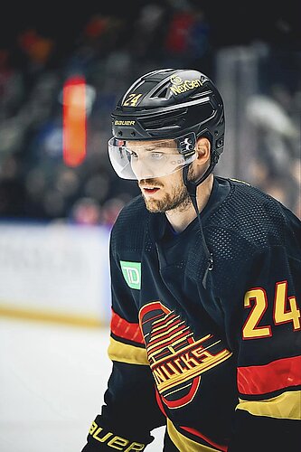 Pius Suter auf dem Hockeyfeld, mit schwarzem Helm und gelber Beschriftung sowie dem schwarz-rot-gelben Trikot der Vanouver Canucks. 